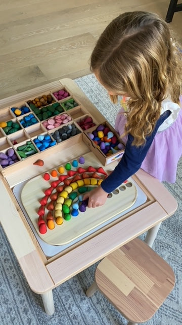 A wooden rainbow board with colorful wooden pieces