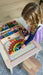 A wooden rainbow board with colorful wooden pieces