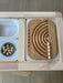 A wooden rainbow board with wooden balls sits on a sensory table