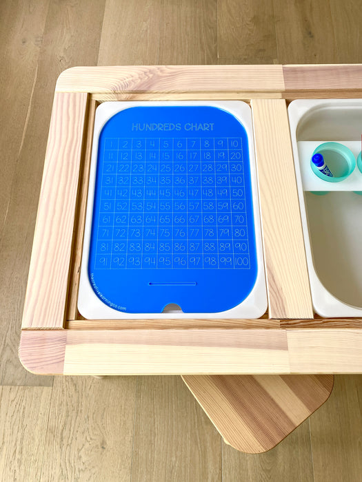 An acrylic hundreds board sits within a sensory flisat table